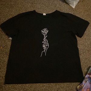 This is a girls black shirt with a hand holding a rose